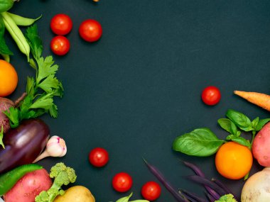 Koyu arka planda çeşitli sebzelerin çerçevesi, üst görünüm.