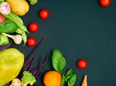 Koyu arka planda çeşitli sebzelerin çerçevesi, üst görünüm.