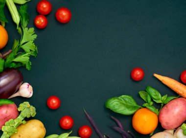 Koyu arka planda çeşitli sebzelerin çerçevesi, üst görünüm.