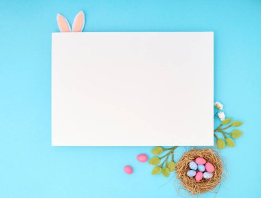 Kopya alanı olan Paskalya tebrik kartı. Mavi arkaplanda kağıt boş.
