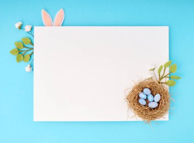 Kopya alanı olan Paskalya tebrik kartı. Mavi arkaplanda kağıt boş.