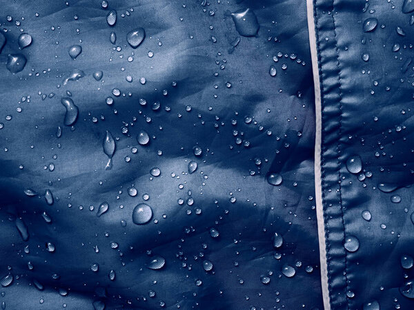 Water drops on waterproof membrane fabric. Detail view of texture of blue waterproof cloth.