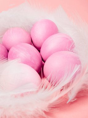 Paskalya yumurtaları ve pembe arka planda tüyler. Mutlu Paskalyalar.