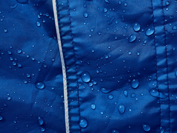 Water drops on waterproof membrane fabric. Detail view of texture of blue waterproof cloth.