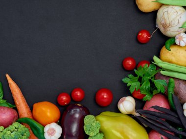 Koyu arka planda çeşitli sebzelerin çerçevesi, üst görünüm.