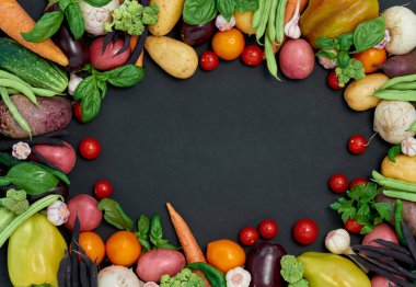 Koyu arka planda çeşitli sebzelerin çerçevesi, üst görünüm.