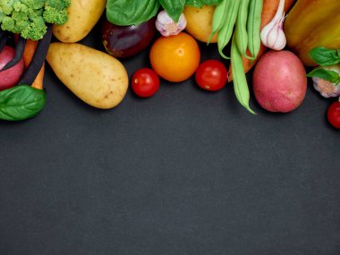 Koyu arka planda çeşitli sebzelerin çerçevesi, üst görünüm.