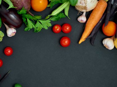 Koyu arka planda çeşitli sebzelerin çerçevesi, üst görünüm.