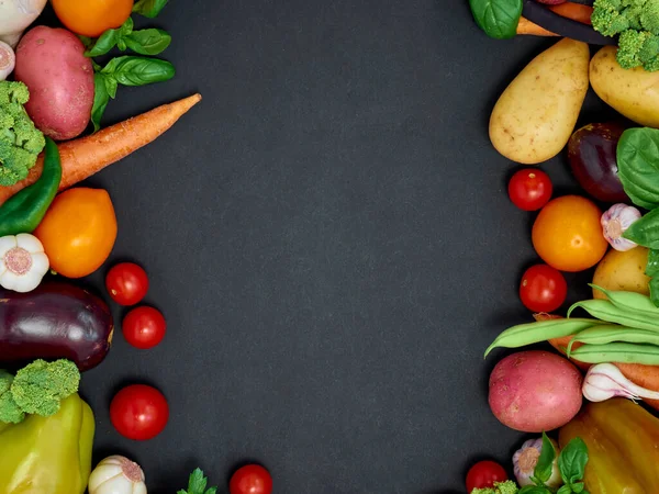 Koyu arka planda çeşitli sebzelerin çerçevesi, üst görünüm.