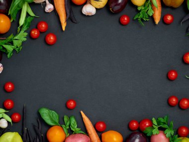 Koyu arka planda çeşitli sebzelerin çerçevesi, üst görünüm.