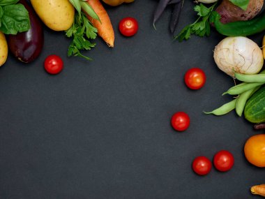 Koyu arka planda çeşitli sebzelerin çerçevesi, üst görünüm.