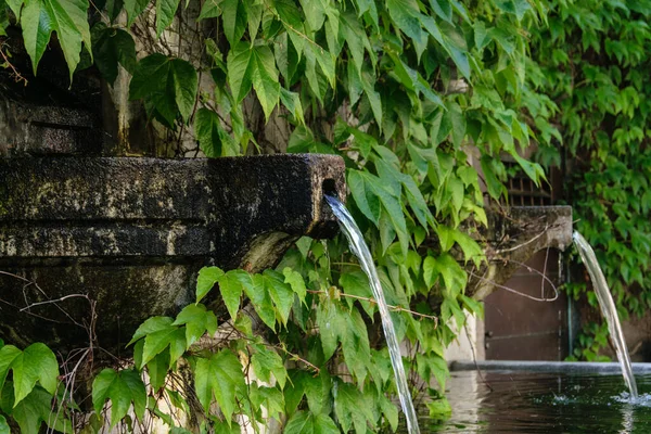 Water overflowing from a stone bowl into a small stone pool in a city park