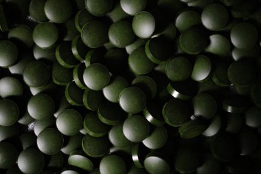 Parlak yeşil spirulina hapları, yakın çekim, düz doku. Vejetaryenler için sağlıklı gıda takviyesi. Anemi ve demir eksikliğinin organik tedavisi. Ana ferritin kaynağı.