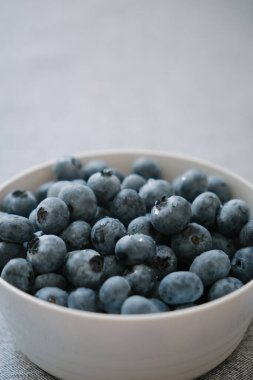 Büyük olgun yaban mersinleriyle dolu beyaz kase, yukarıdaki yazı için kopyalama alanı. Taze yaz meyveleri vitamin ve mikro elementlerin doğal kaynağıdır. Sağlıklı beslenme, vejetaryen beslenme