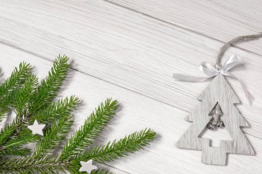 Noel ya da yeni yıl dekorasyonları: köknar dalları ve beyaz tahta üzerinde Noel ağacı şeklinde bir oyuncak. Düz konum, boşluğu kopyala.