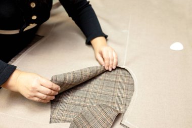 Paltoları kesme süreci. Kadınların elleri desenden kesilen kumaşı ortaya çıkarıyor. Kol kesiği