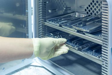 Kadın hemşire diş sağlığı aletlerini sterilize ediyor. Diş hekimliği