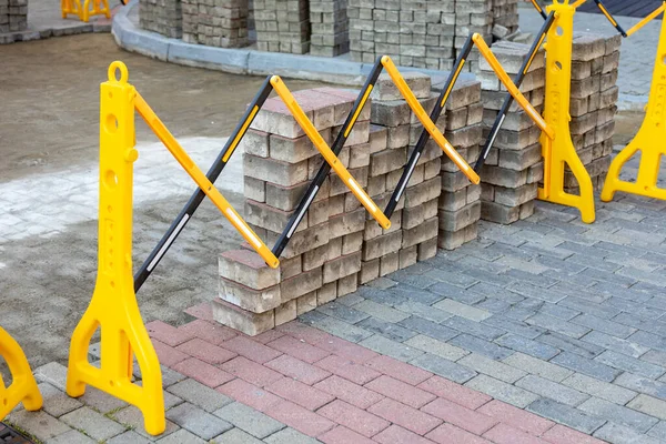 Plastic safety barrier protects road work area. Yellow-black plastic fence near street repair site. Outdoor construction work, road repair, protective fence. — Stock Photo, Image