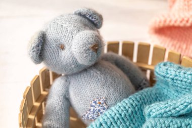 Gri örülü bir ayı, örülmüş bir battaniyeyle kaplı küçük bir ahşap sepetin içinde yatıyor. Çocuk uykusu kavramı