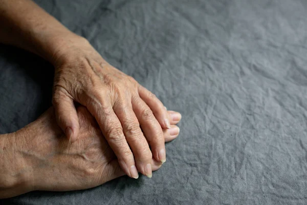 Ręce starszego seniora na szarym wyblakłym obrusie. Starsza pani doświadcza ciężkich bólów reumatycznych stawów, masażu, rozgrzewania ramienia. Przestrzeń kopiowania — Zdjęcie stockowe