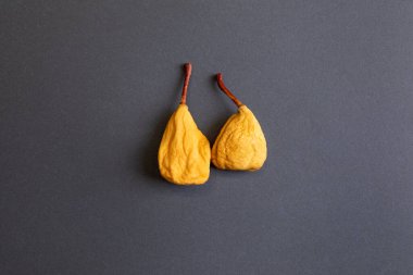 Koyu gri arka planda iki sarı kurutulmuş armut. Sağlıklı yeme kavramı