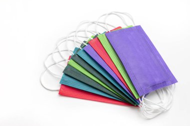 Pembe arka planda çok renkli koruyucu maskelerin üst görüntüsü. Bireysellik kavramının korunması ve salgın sırasında koronavirüs enfeksiyonuna karşı solunum koruması. Yeni gerçeklik