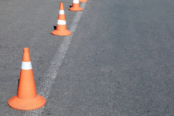 Bright orange traffic cones on asphalt road. Traffic signal cones are considered universal products, with their help you can quickly and easily ensure the safety of all road