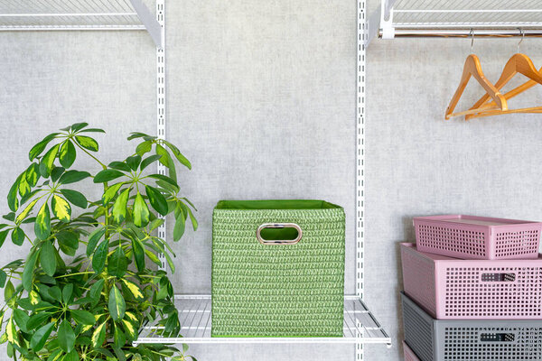 Green box with handles on metal shelf in dressing room. Modern and fashionable wardrobe with metal shelves, storage system clothes.