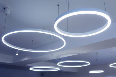 Yuvarlak modern LED lambalı tavan. Tavanın altına floresan lambaları asılmış. Dikkatli enerji tüketimi, enerji tasarrufu kavramı.