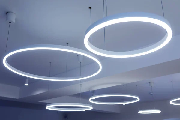 Yuvarlak modern LED lambalı tavan. Tavanın altına floresan lambaları asılmış. Dikkatli enerji tüketimi, enerji tasarrufu kavramı.