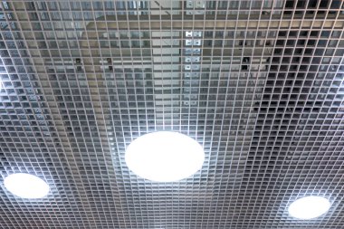 Ticari bir binanın tavanında üç tane LED lamba var. Askıda asılı kalan tavan, bir alışveriş merkezi veya ofis binasının içini güzel bir mimari görünüş yaratır. - Evet. Boşluğu kopyala