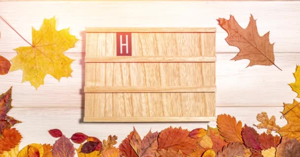 Animazione stop motion di una bacheca di legno con una serie di frasi di testo Ciao Autunno, mela matura rossa e foglie secche cadute su uno sfondo di legno. Stagione autunnale, tempo di raccolta, leaffall, concetto autunnale. — Video Stock