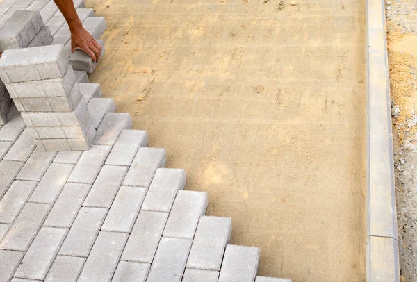 Bricklayers hand lays paving slabs in prepared sand mixture. Process of laying sidewalk, landscaping garden — Stock Photo, Image