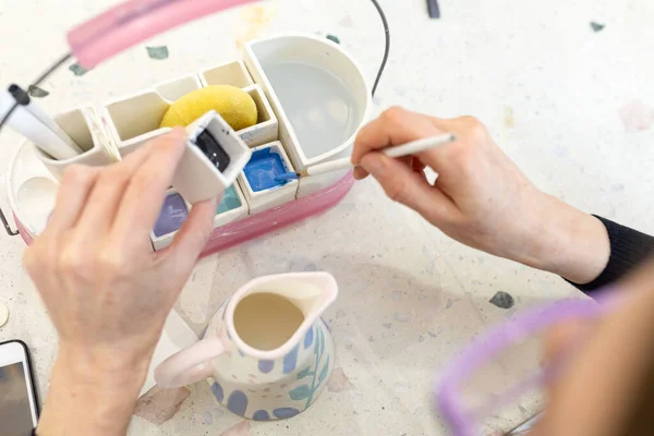 Womens hands mix paint for coloring ceramic milk jug in workshop — Stock Photo, Image