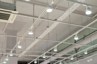Modern bir depoda parlak ışıkları olan bir tavan, alışveriş merkezi binası, ofis veya diğer ticari gayrimenkul eşyaları. Tavanın altındaki raylarda LED ışıkları