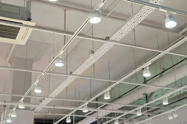 Modern bir depoda parlak ışıkları olan bir tavan, alışveriş merkezi binası, ofis veya diğer ticari gayrimenkul eşyaları. Tavanın altındaki raylarda LED ışıkları