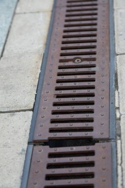 Yolun kenarında paslı bir rögar ızgarası var. Şehir altyapısı, sel baskınlarına karşı yol koruması, şiddetli yağmurlar