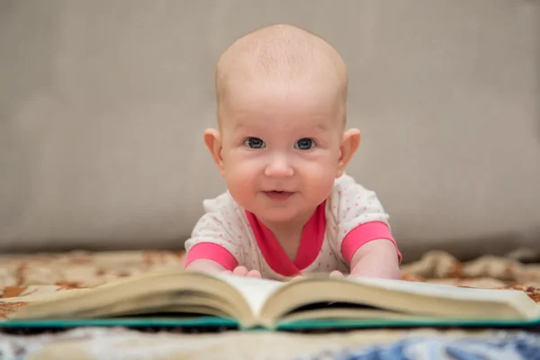 Bebê deitado na barriga lendo um livro — Fotografia de Stock