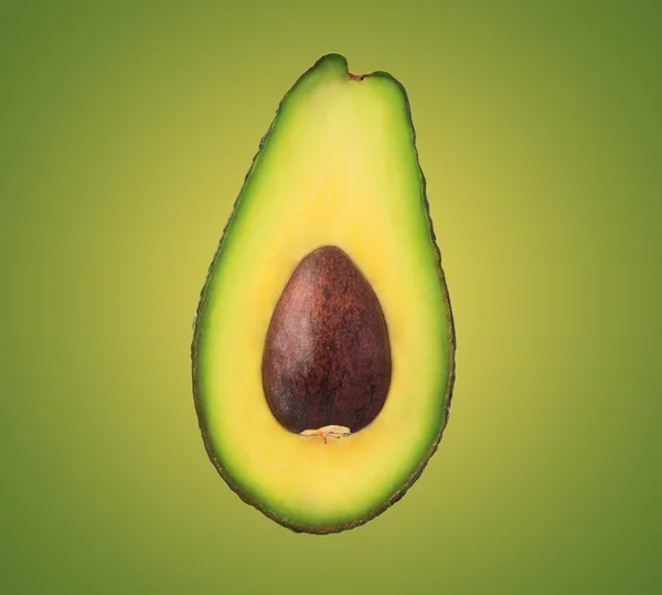 Yeşil arka plan üzerinde izole taşlı yarım avokado