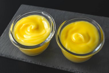 Limonlu puding ya da limonlu krema. Siyah arka planda cam kaseler, tatlı krema, lezzetli tatlı.