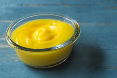 Cam bir kasede leziz limon ezmesi. Mavi ahşap arka plana yakın.