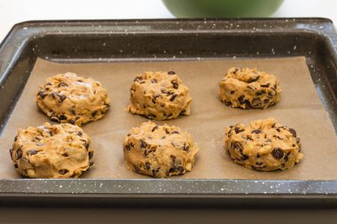 Çikolata parçalı kurabiyeler parşömen kaplamalı fırın kağıdına yakın.