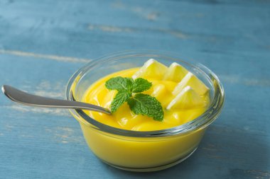 Naneli ve dilimlenmiş limonlu limonlu cam kasede servis edilen limonlu puding veya limonlu pasta.