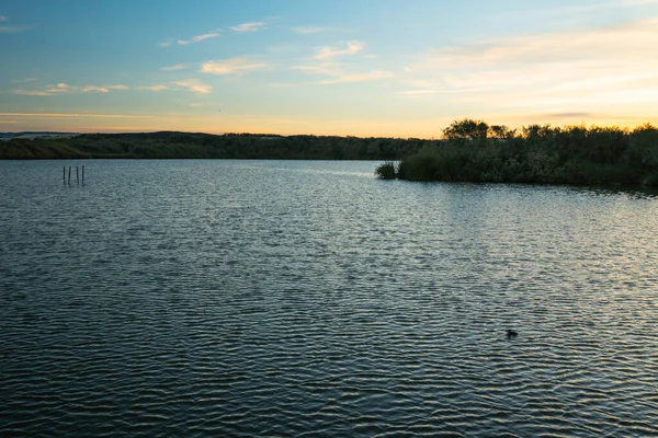 Gölde gün batımı, renkli gökyüzü ve güzel yansımalı sakin su.