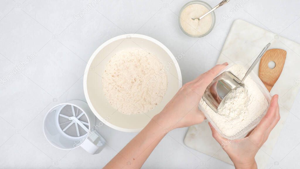 Mixing yeast starter and flour in a bowl. Step by step bread dough recipe, close upview from above, woman hands