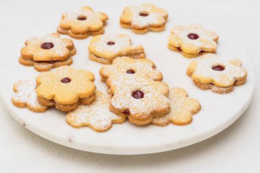 Ahududu reçeli ile doldurulmuş çiçek şeklindeki kurabiyeler beyaz arka planda yakın plan