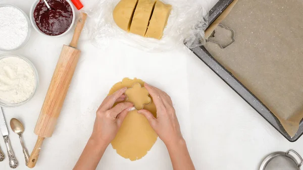 花形のショートブレッドクッキーにラズベリージャムのレシピが詰まっています クッキーカッターを使ってクッキーをスタンプする女性の手 — ストック写真