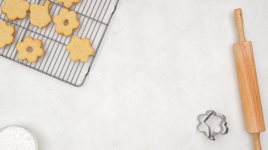 Food background. Fresh baked cookies on cooling rack, wooden rolling, cookie cutters, flat lay with copy space