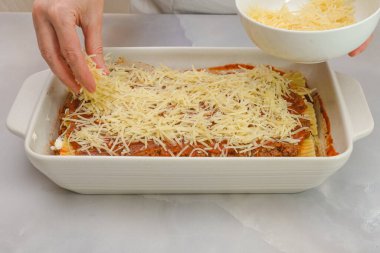 Parmesan peynirli lazanya. Adım adım biftek lazanya tarifi. Ön manzara, kadın eli, mermer arka plan.