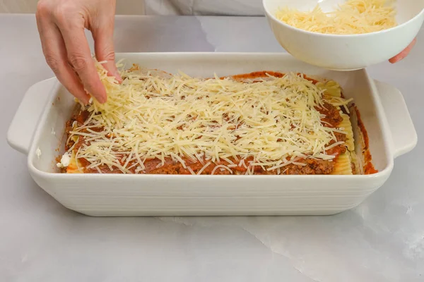 Parmesan peynirli lazanya. Adım adım biftek lazanya tarifi. Ön manzara, kadın eli, mermer arka plan.